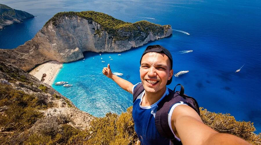 Happy couple of travelers taking selfie photo on a sunset beach - Young man  and woman having fun in summer vacation - Two friends enjoying summer  moment - Lifestyle and travel concept.