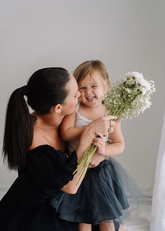 Mother daughter posing with a white flower
